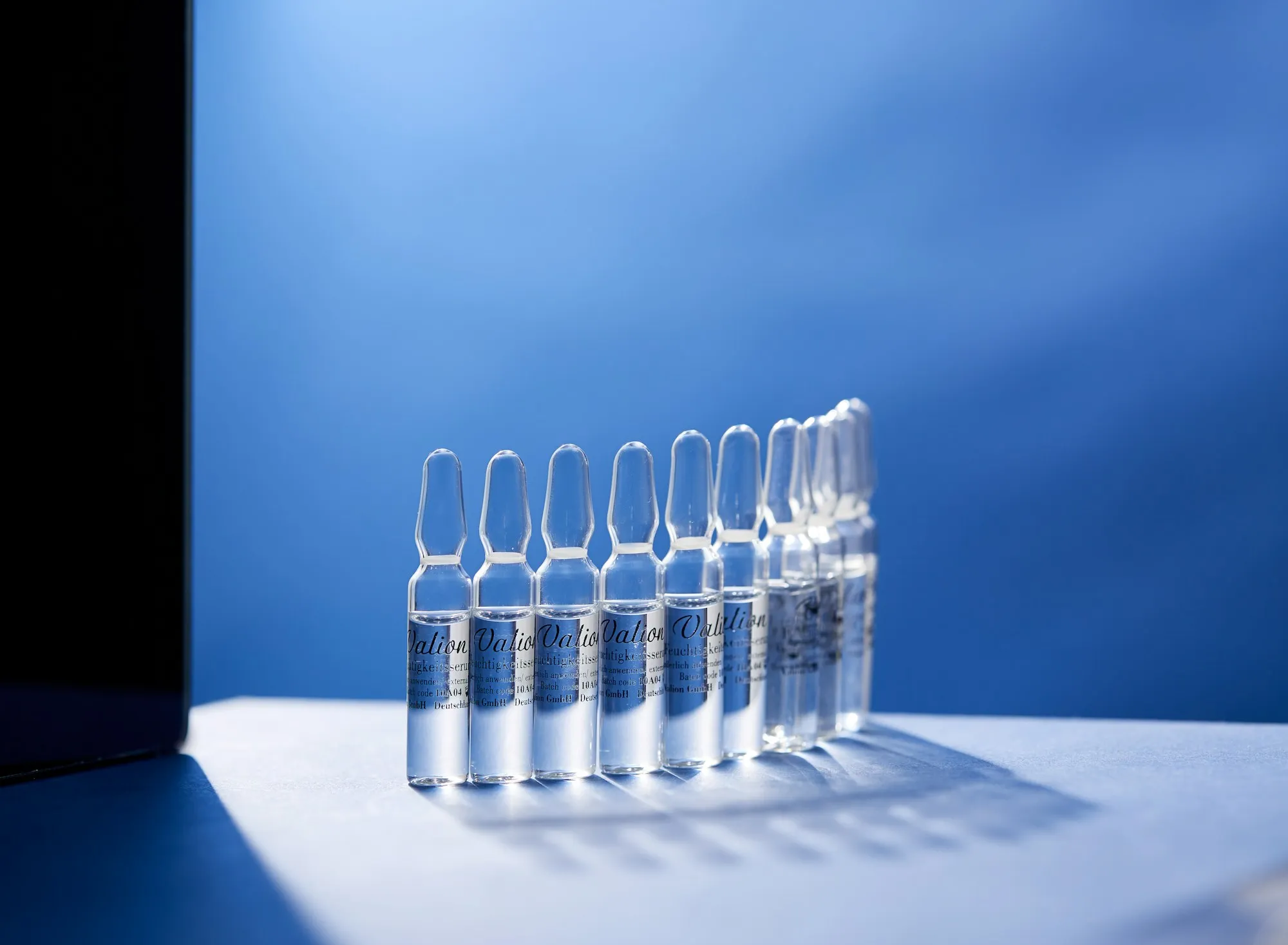 Row of clear glass ampoules on a blue background