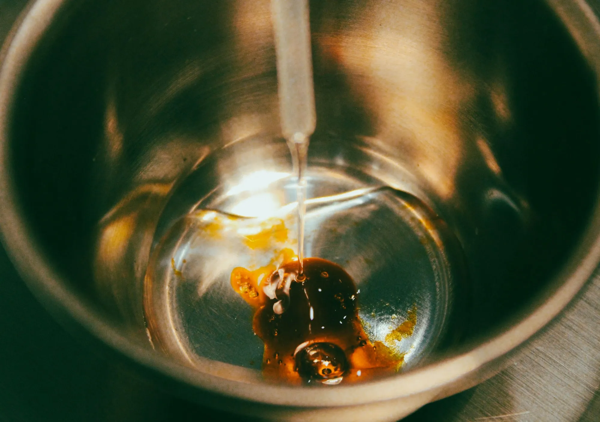 Pipette dripping oil into a glass bowl