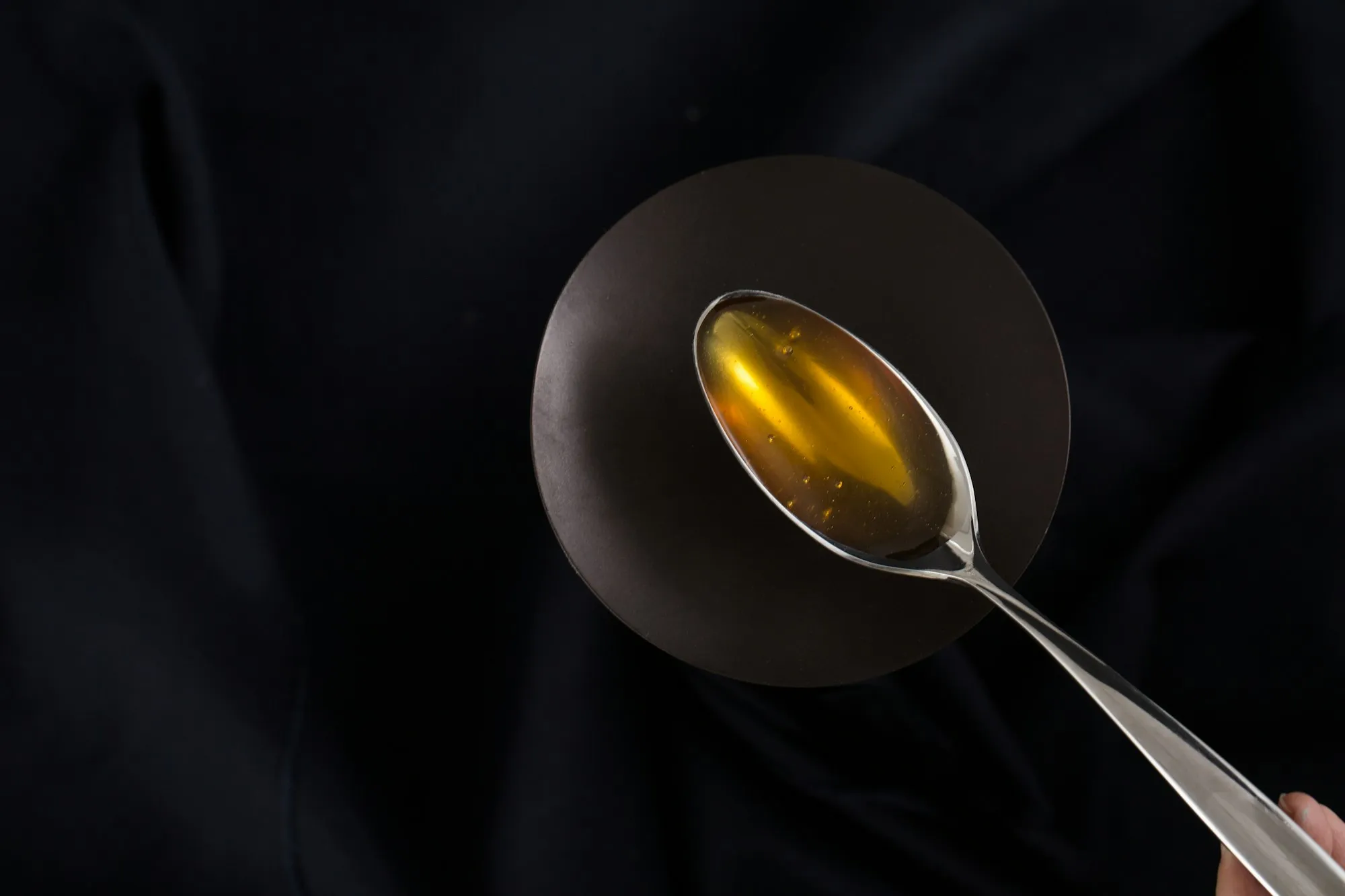 Spoon of golden syrup on a dark background